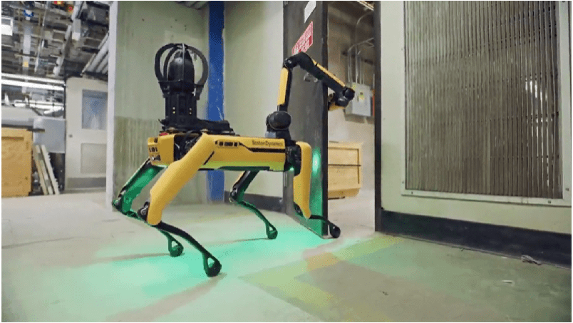 Spot using its arm to move through a doorway in an industrial facility