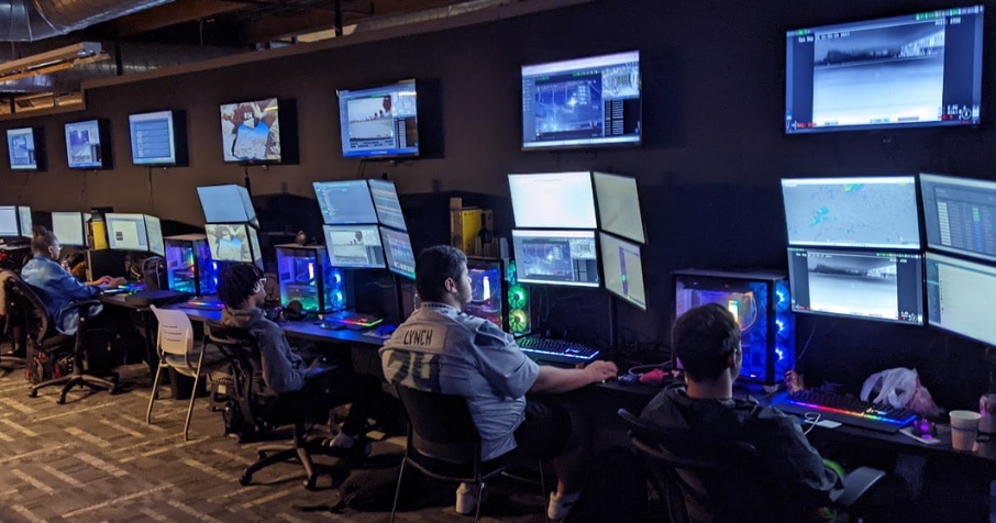 Security personnel sit in front of a bank of monitors tracking security rounds performed by robots