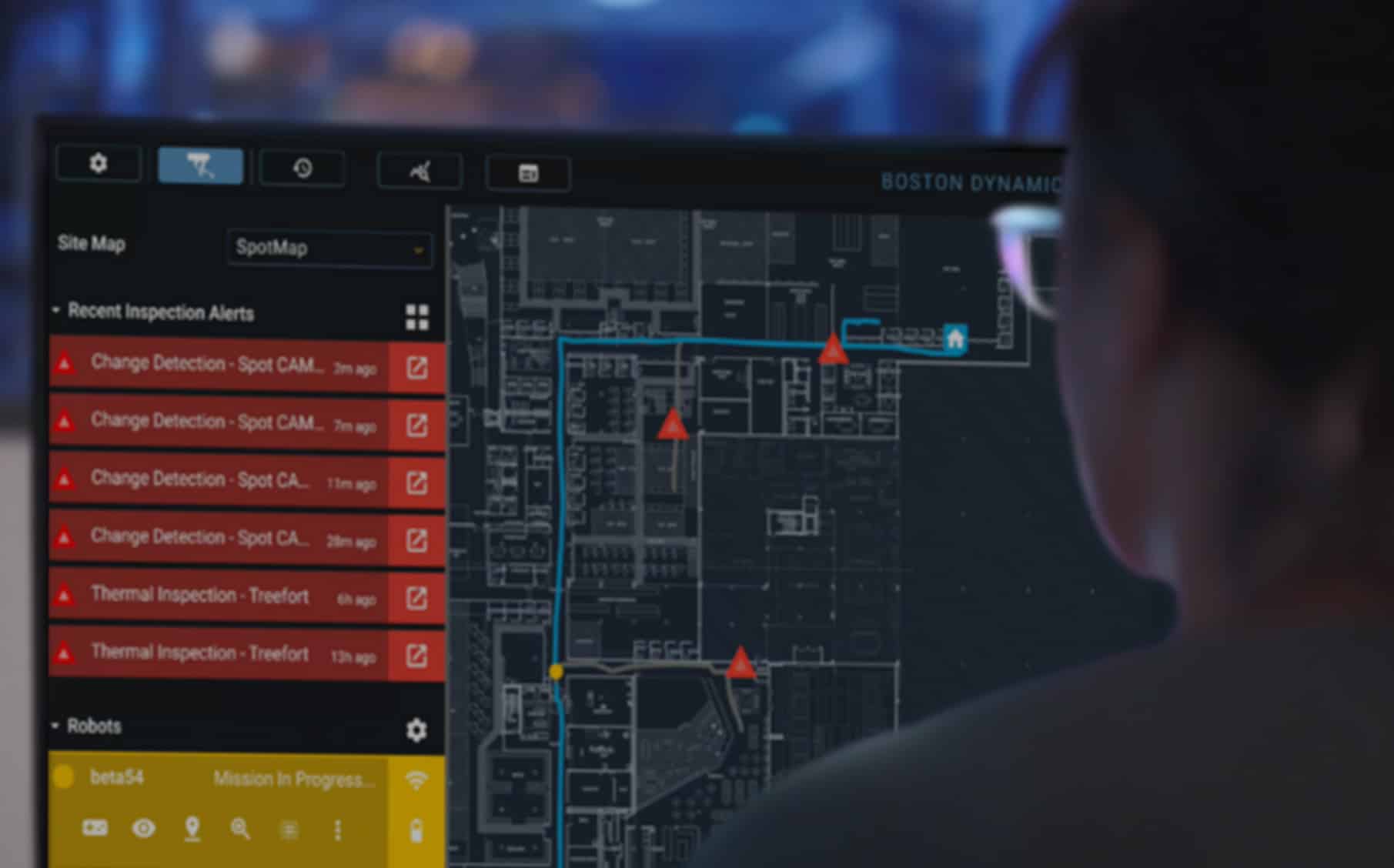 A woman views alerts overlaid on a facility map in Orbit