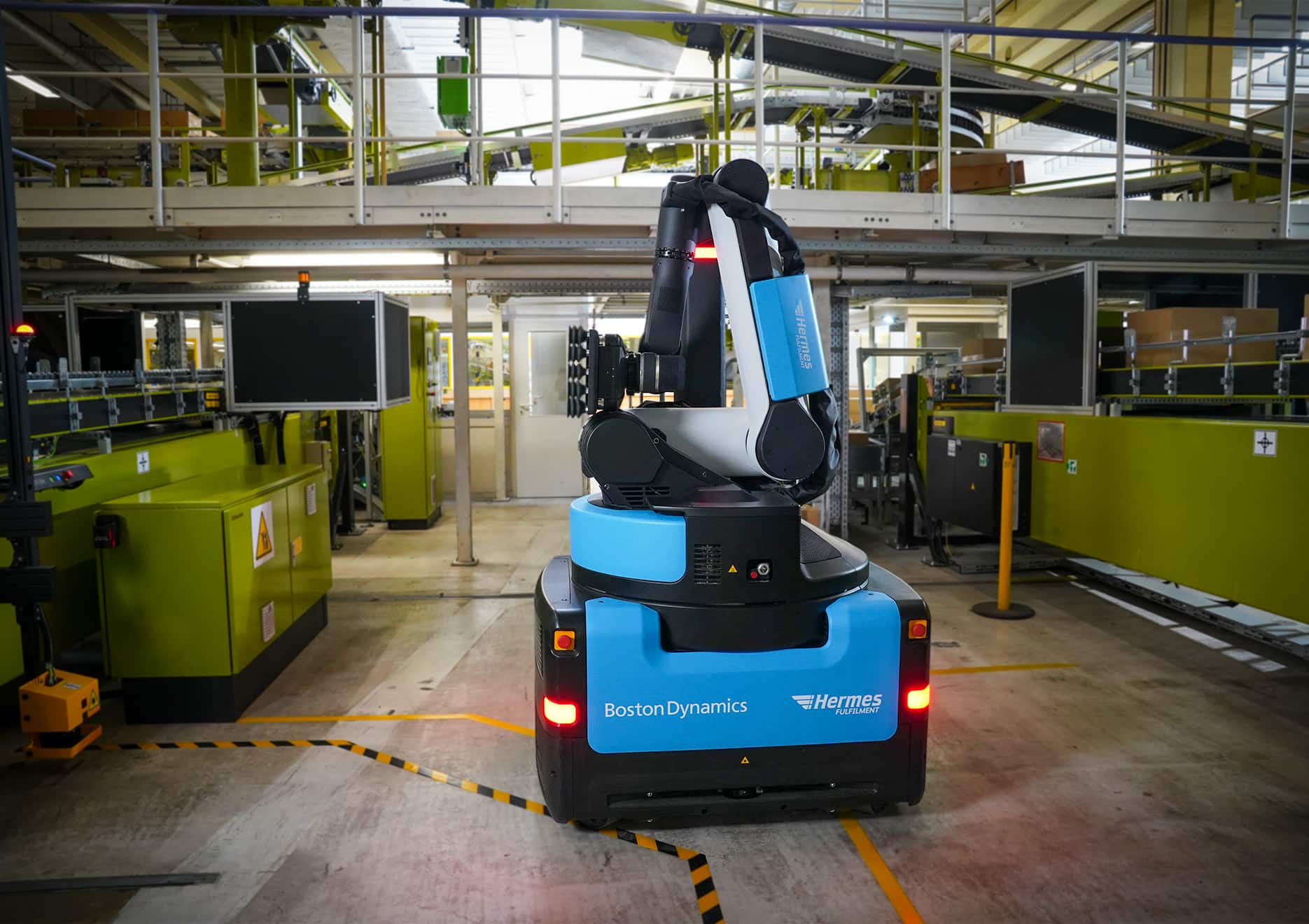 A blue Stretch robot with the Hermes Fulfilment logo poses in a warehouse