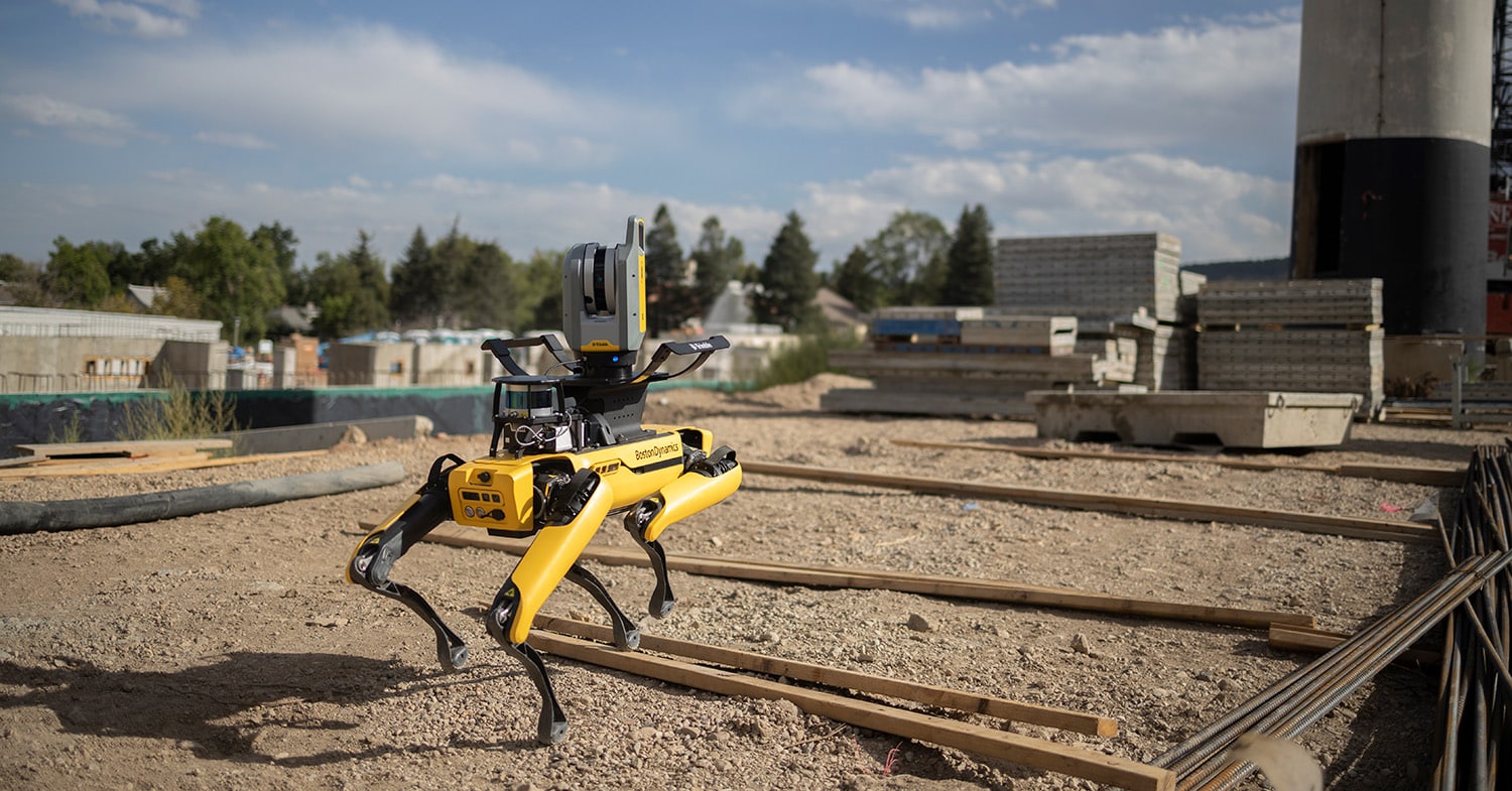 Spot walks over lumber on an outdoor construction site