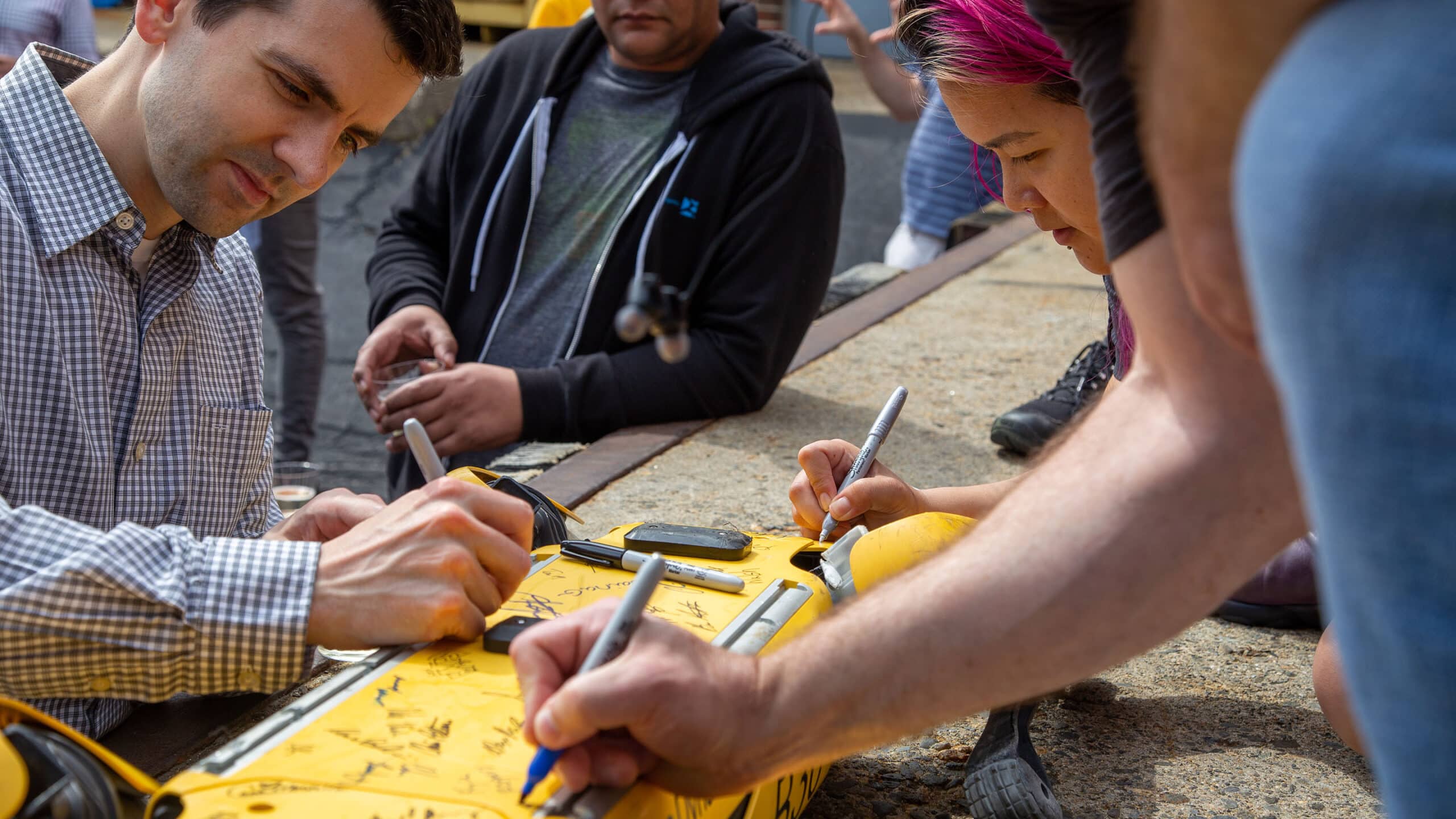 A group of employees sign a Spot robot