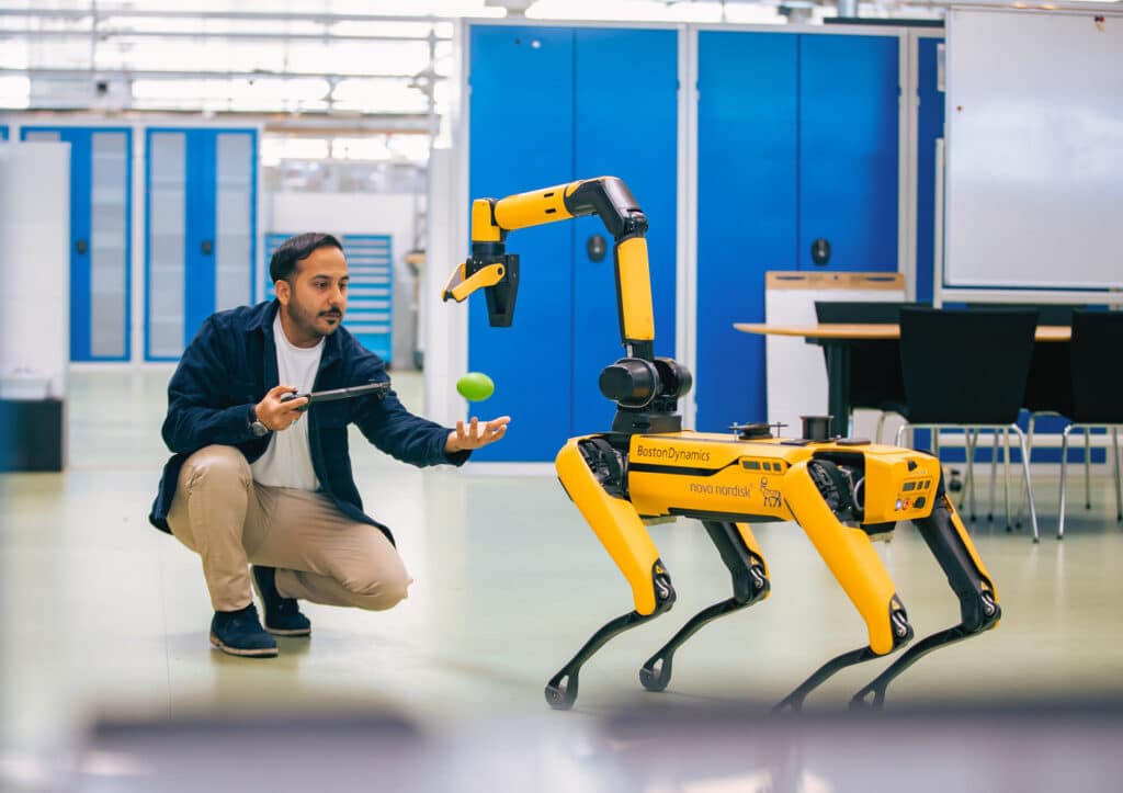 A robotics engineer interacts with Spot in a pharmaceutical facility