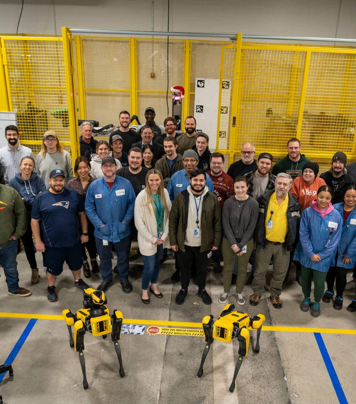 A group photo showing Boston Dynamics team members posing with 2 Spot robots