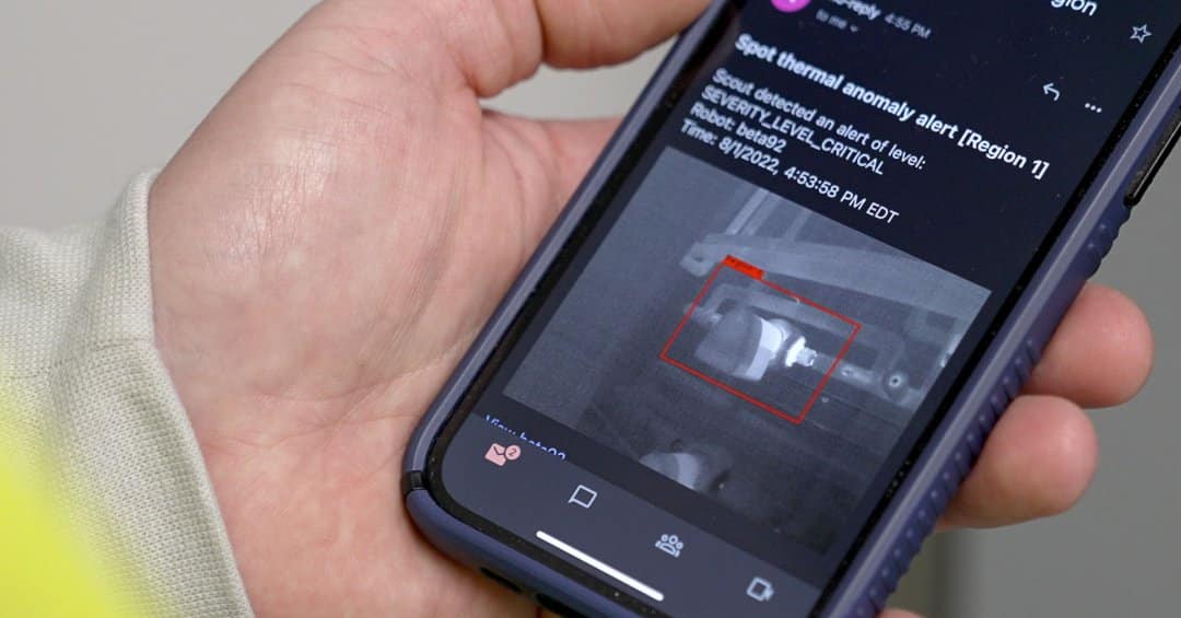 A mobile phone in an operator's hang showing an alert for a thermal anomaly